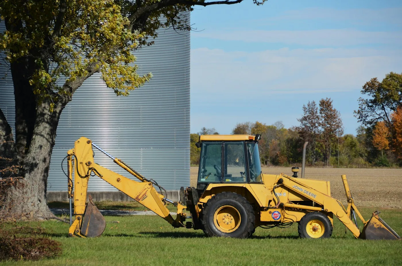 Backhoe loader beside a tree and exposed ground